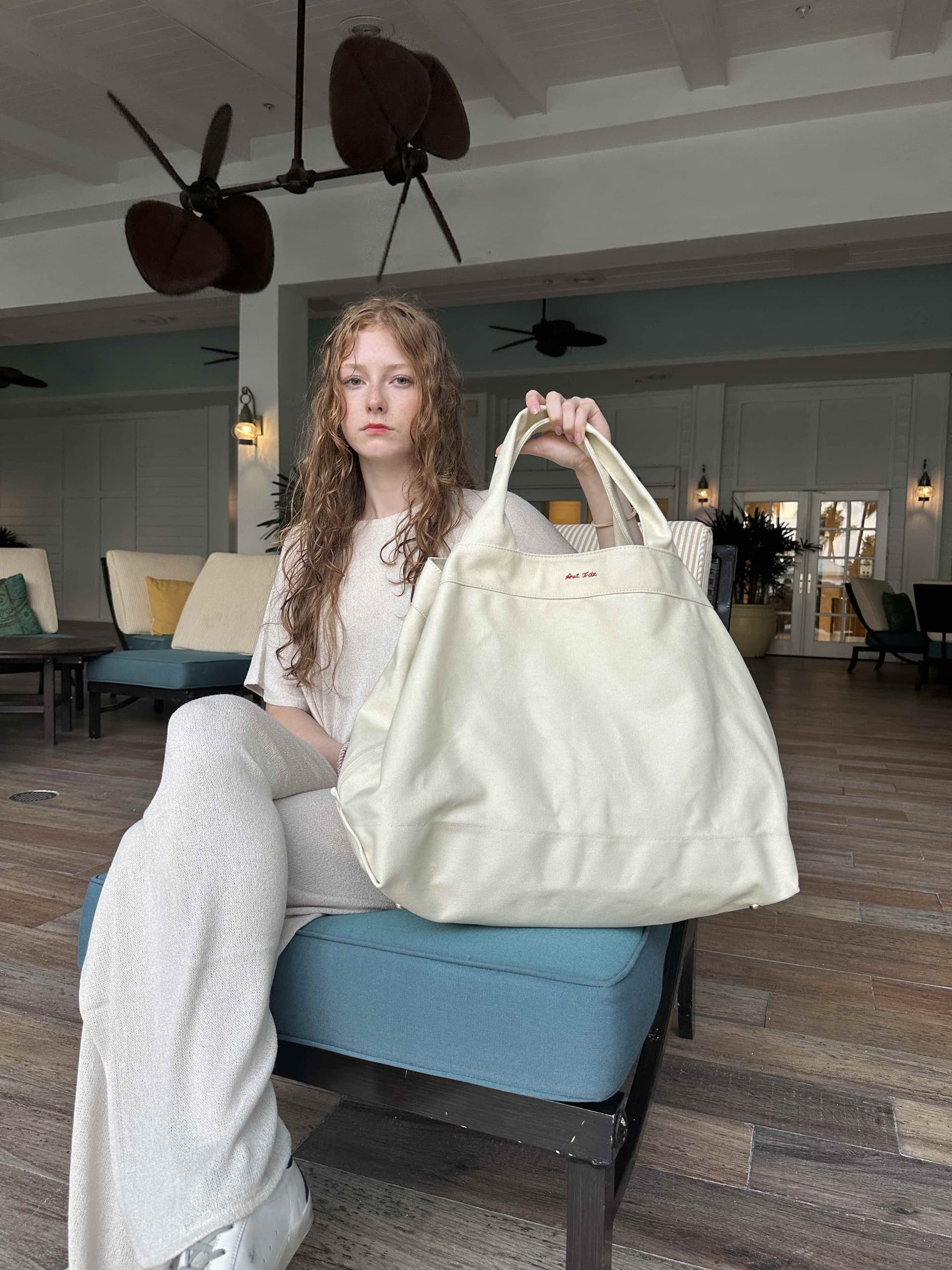 Model holding canvas tote indoors